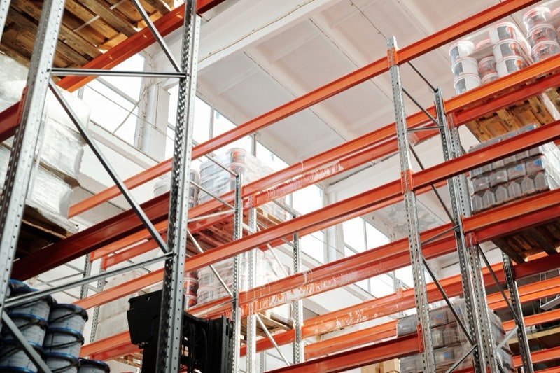 Looking up at tall orange warehouse racking stacked with pallets